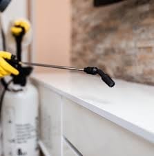 Close-up of a pressure washer nozzle spraying water on a white surface with yellow equipment visible in background
